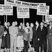 A group of protestors gather on an airplane tarmac as Dalton Trumbo awaits his plain.