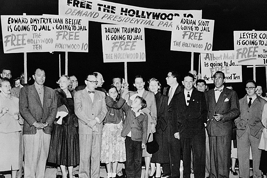 A group of protestors gather on an airplane tarmac as Dalton Trumbo awaits his plain.