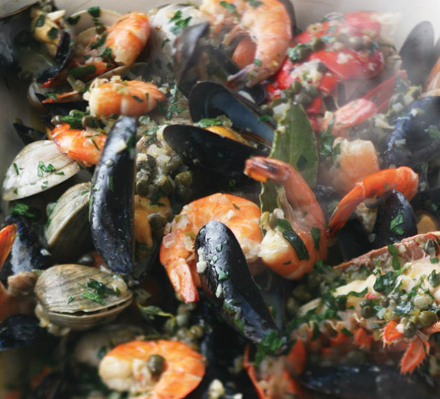 A bowl of shellfish, lemon, shrimp, and rice.