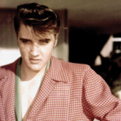 A young Elvis Presley poses for a photo wearing a red, checkered sports jacket.