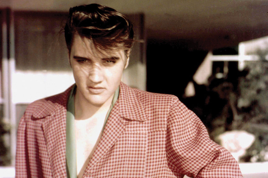 A young Elvis Presley poses for a photo wearing a red, checkered sports jacket.