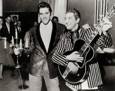 Liberace holds Elvis' guitar while Elvis holds Liberace's candelabra. 