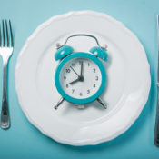 A dinner plate with an alarm clock on it.