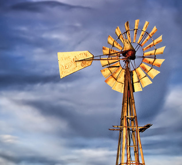 A windmill on a firm in the American midwest.