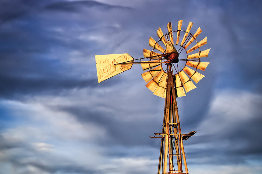 A windmill on a firm in the American midwest.