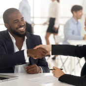 Business workers shake hands at a table inside their office