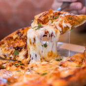 A slice of pizza being lifted from a plate.