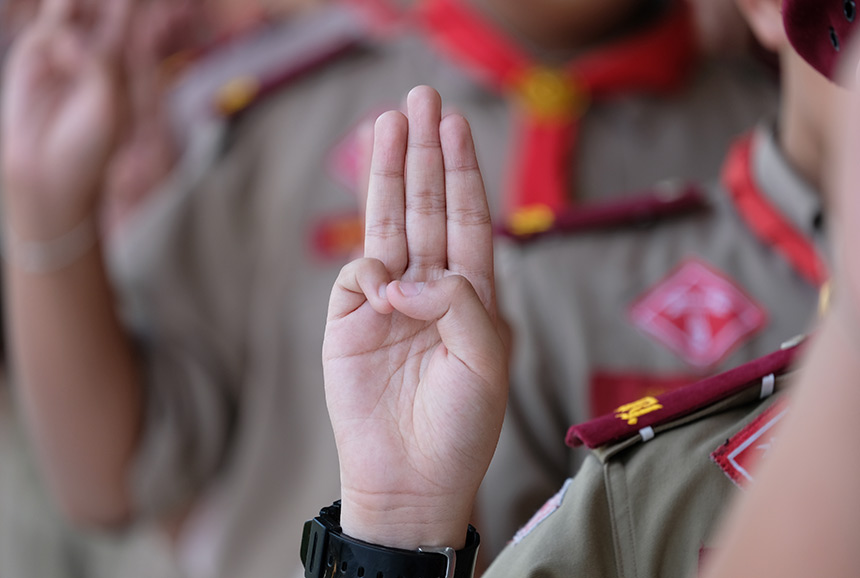A boy scout giving the scout salute.