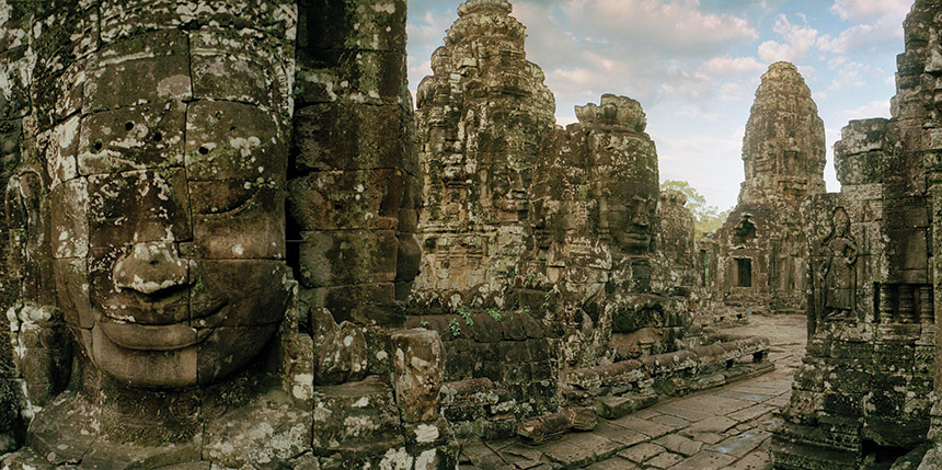 A large stone face of a Khmer ruler sites in the Angkor Thorn ruins