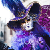 Mardi Gras celebrant dressed in a mask and a flowery gown