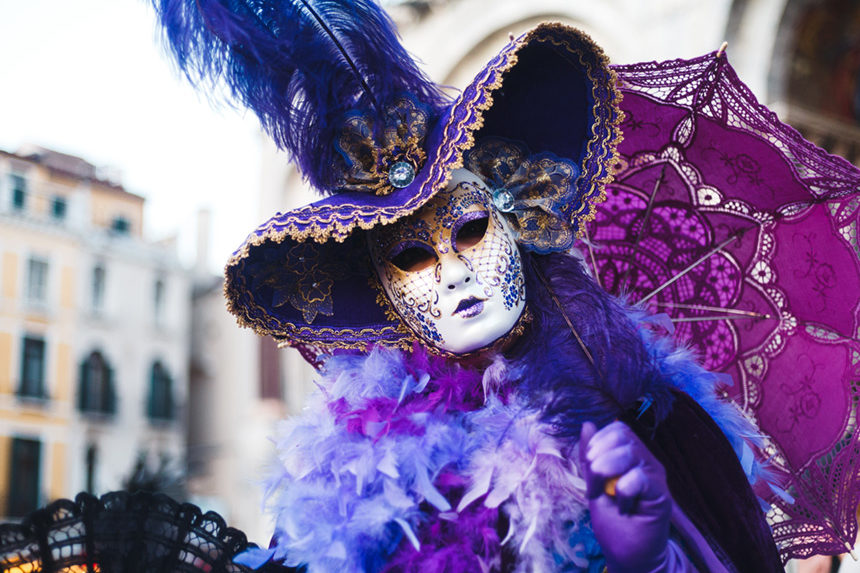 Mardi Gras celebrant dressed in a mask and a flowery gown