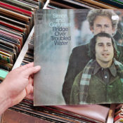 Man holding a copy of Simon and Garfunkel's LP "Bridge Over Troubled Water"