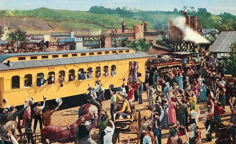 A scene from the film, The Harvey Girls, featuring a crowd waving at a train car.