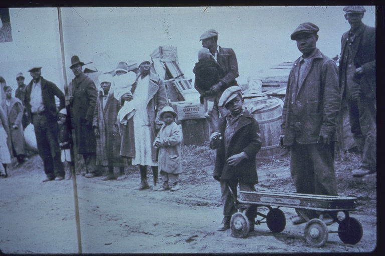 African American sharecroppers, who were evicted from their homes, stand along the side of a road