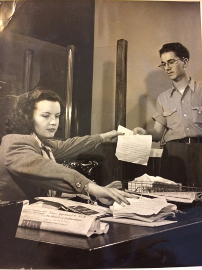 A young Val Laudner hands a piece of paper to a co-worker at the Chicago Daily News' office.