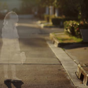 Transparent outline of a young girl stands in an empty street. Signifies a missing child.