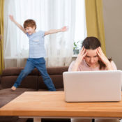 A mother nurses a headache as she attempts to handle remote work and parenting at once.