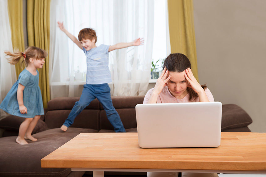 A mother nurses a headache as she attempts to handle remote work and parenting at once.