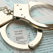 Handcuffs lie atop a stack of tax forms