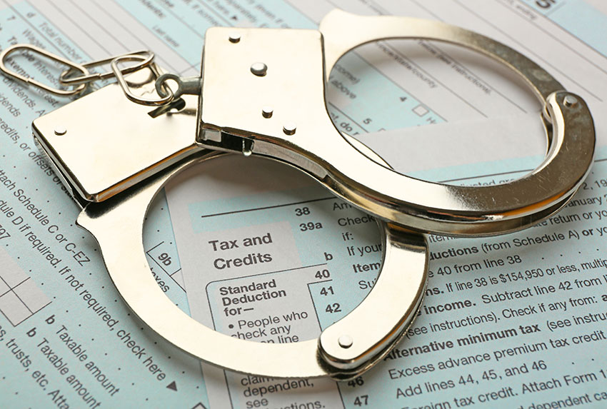 Handcuffs lie atop a stack of tax forms