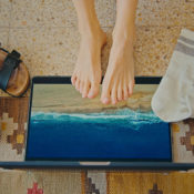 Feet on a laptop that has a beach on its screen