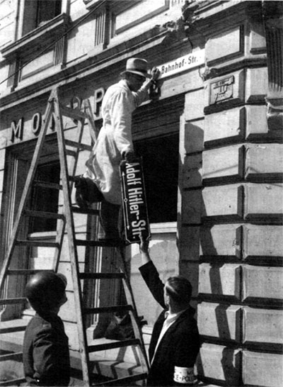 Allied employees remove a street sign named after Adolf Hitler