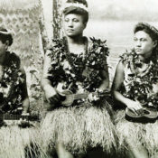 Women in traditional Hawaiian dress play their ukuleles