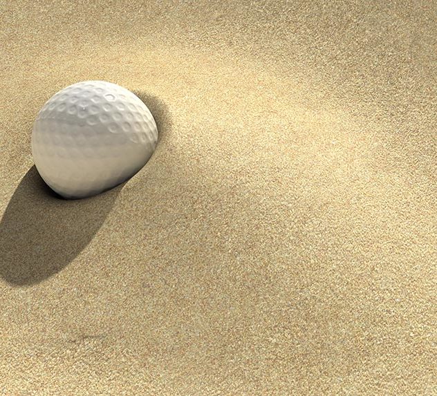 A golf ball half-buried in a sand bunker