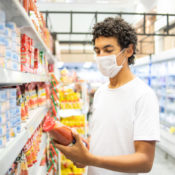 A young man in a grocery store wears a protective mask during the COVID-19 pandemic.