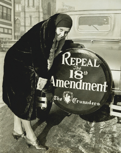 Woman poses next to a spare tire cover that reads "Repeal the 18th Amendment"