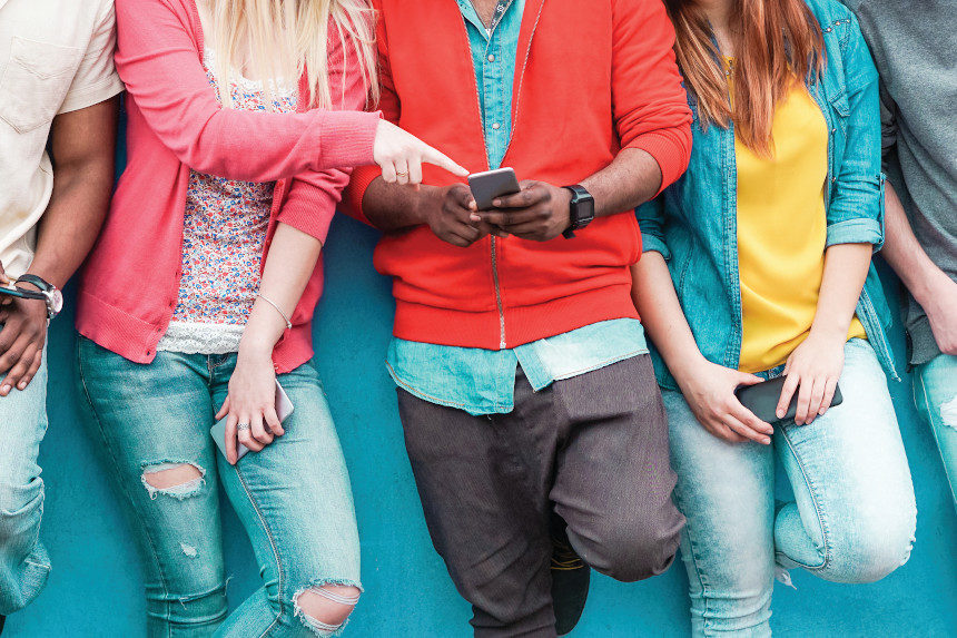 A group of millennials looking at a mobile phone.