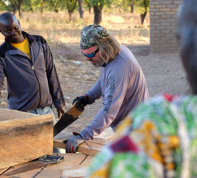 United Aid Foundation founder John Alex saws wood in a Malian villiage