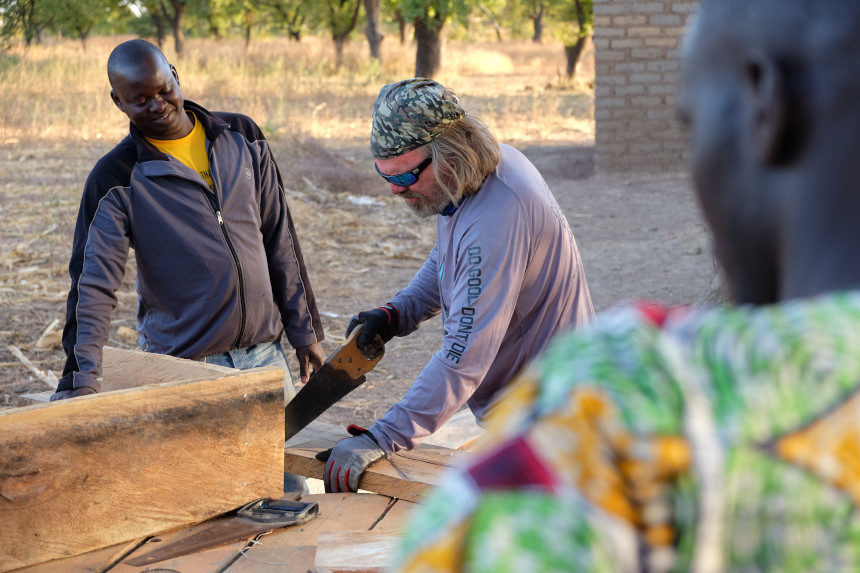 United Aid Foundation founder John Alex saws wood in a Malian villiage