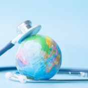 A stethoscope rests on a miniature globe