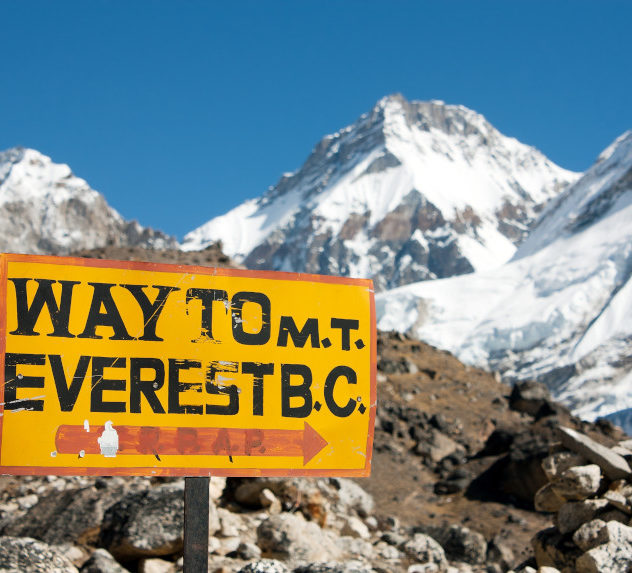 A signpost next to the path to Mount Everest that reads "WAY TO M.T. EVEREST B.C."