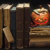 A grinning Jack-o'-Lantern rests on dusty old books.