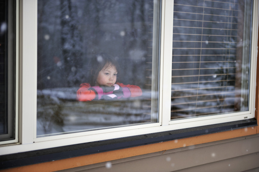 Kid looking outside during a snow storm