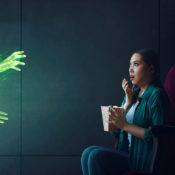 Woman stares in shock while a ghost reaches out of her television