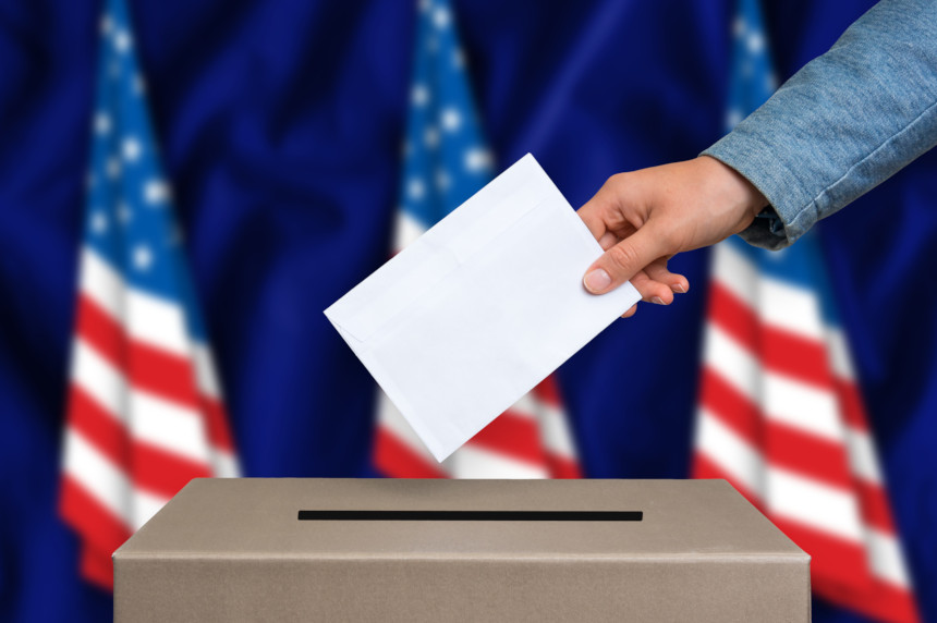 Woman sticking a ballot into a ballot box.