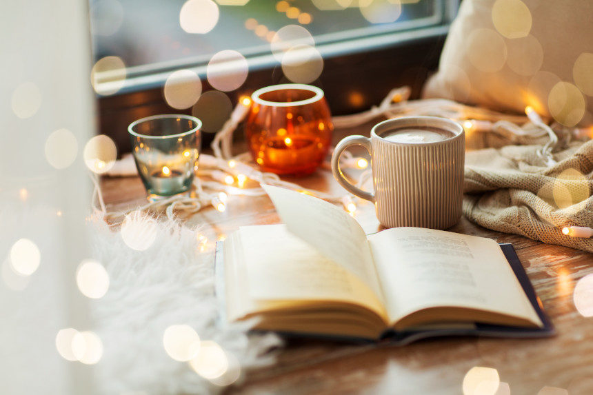 A book and coffee mug with candles.
