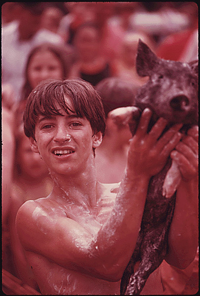 Young teenager holds up a greased pig he caught during a coal company's picnic