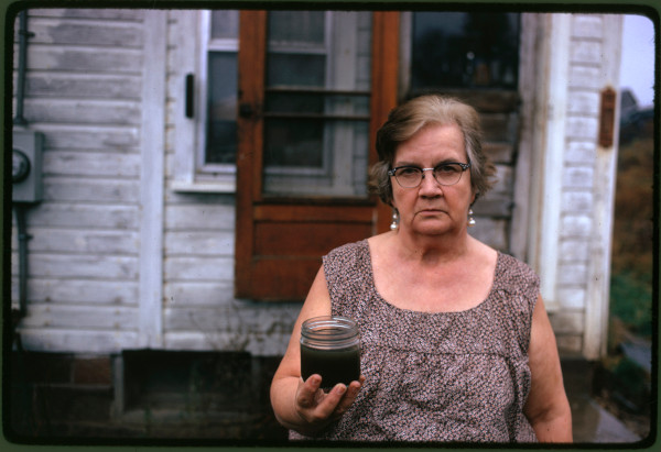 A woman holds a jar of polluted, undrinkable water