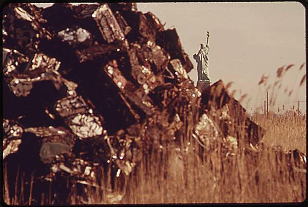 The Statue of Liberty can be seen across from a landfill