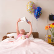 A sick girl in a hospital bed reading a get well card.