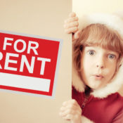 kid hiding behind a For Rent sign