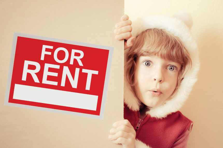 kid hiding behind a For Rent sign