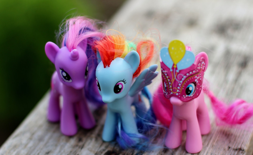 Three My Little Pony dolls on a wooden bench