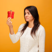 Woman looks at a small gift with a sour expression