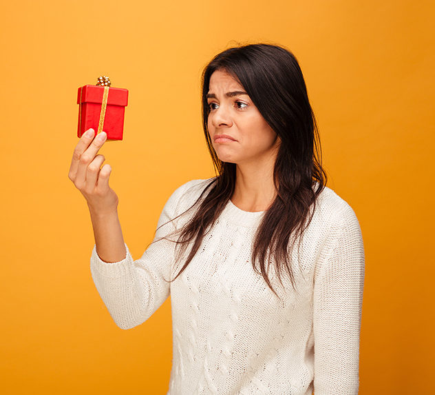 Woman looks at a small gift with a sour expression