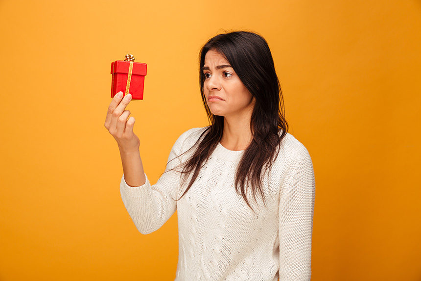 Woman looks at a small gift with a sour expression
